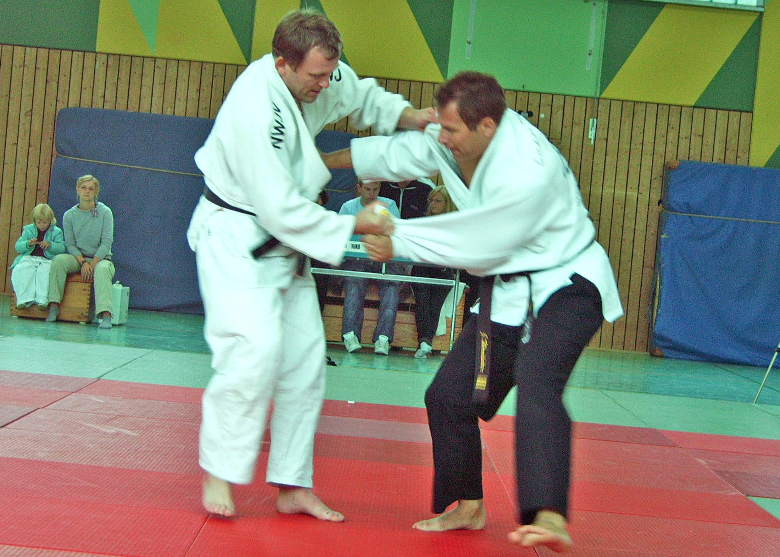 Judoka im Kampf auf roten Matten.