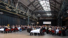 Pubikum auf roten Stühlen in alter Industriehalle
