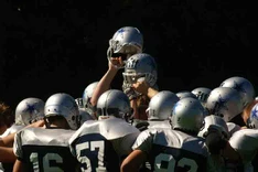 American Footballer im Pulk mit silbernen Helmen. Zwei davon werden in die Höhe gestreckt.