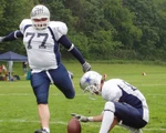 Kicker beim American Football tritt von seinem Teamkollegen gehaltenes Lederei.