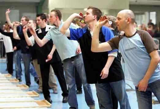 Konzentrierte Dartspieler in Aktion, die mit dem Pfeil in der Hand das Dartbrett anvisieren.
