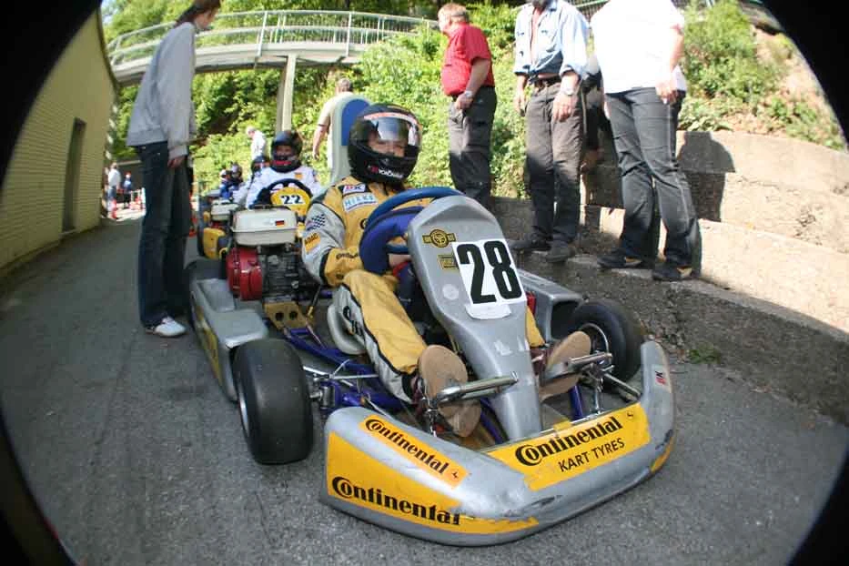 Junger Rennfahrer in gelbem Outfit im Kart mit der Nummer 28.