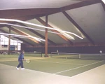 Tennishalle mit weißer Decke und grünem Filzboden.
