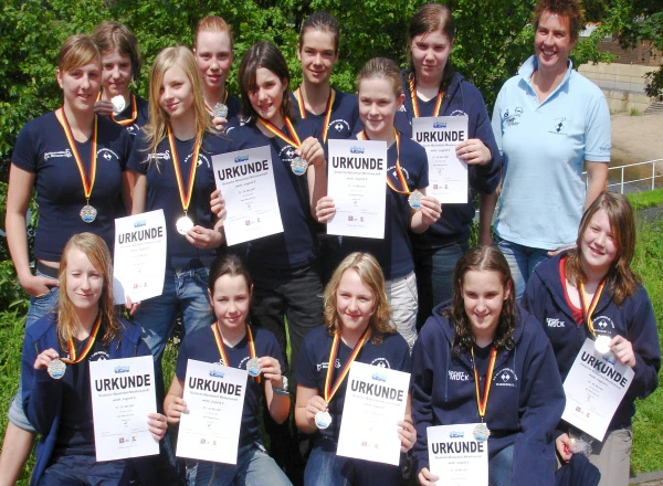 Mannschaft und Trainerin der Wasserballerinnen in blauen T-Shirts.