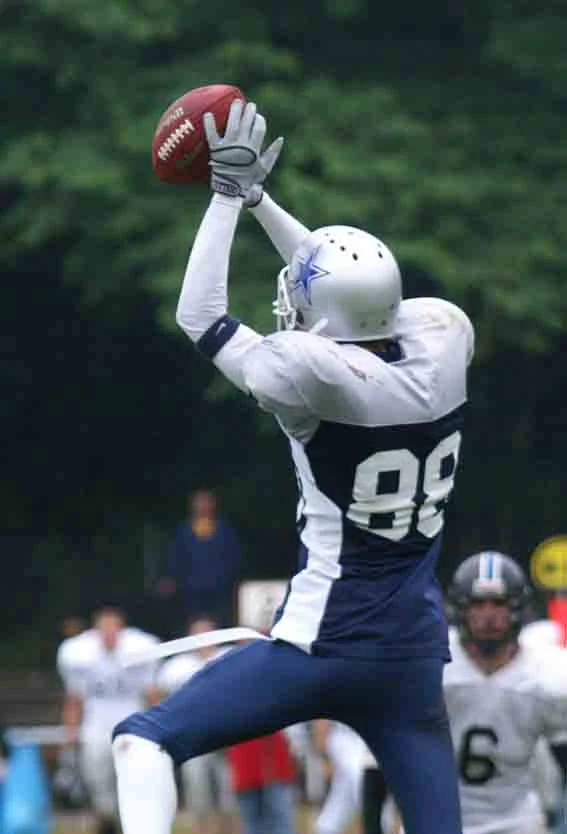 American Footballer in blauem Trikot beim Sprung und Fangen.