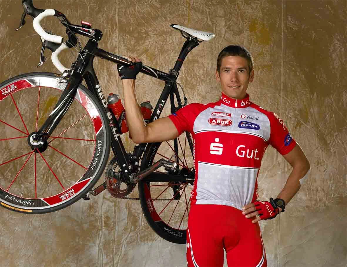 Darren-Lapthorne im rot-weissen Sparkassen-Trikot stemmt sein Rad mit einem Arm.