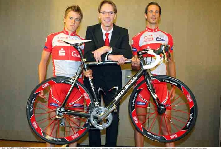Radsportler des Team Sparkasse mit Rennrad und dem Manager.